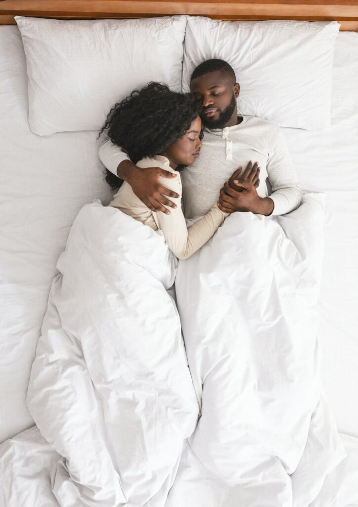 Black family couple lying and cuddling in bed, sleeping together