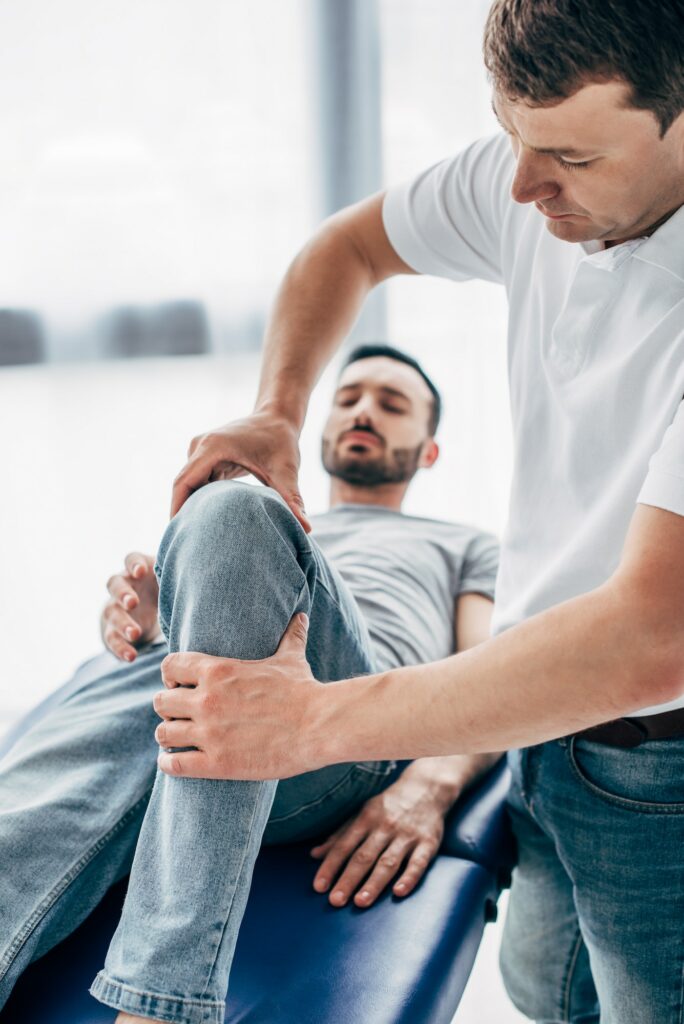 selective focus of Physiotherapist massaging leg of patient in hospital