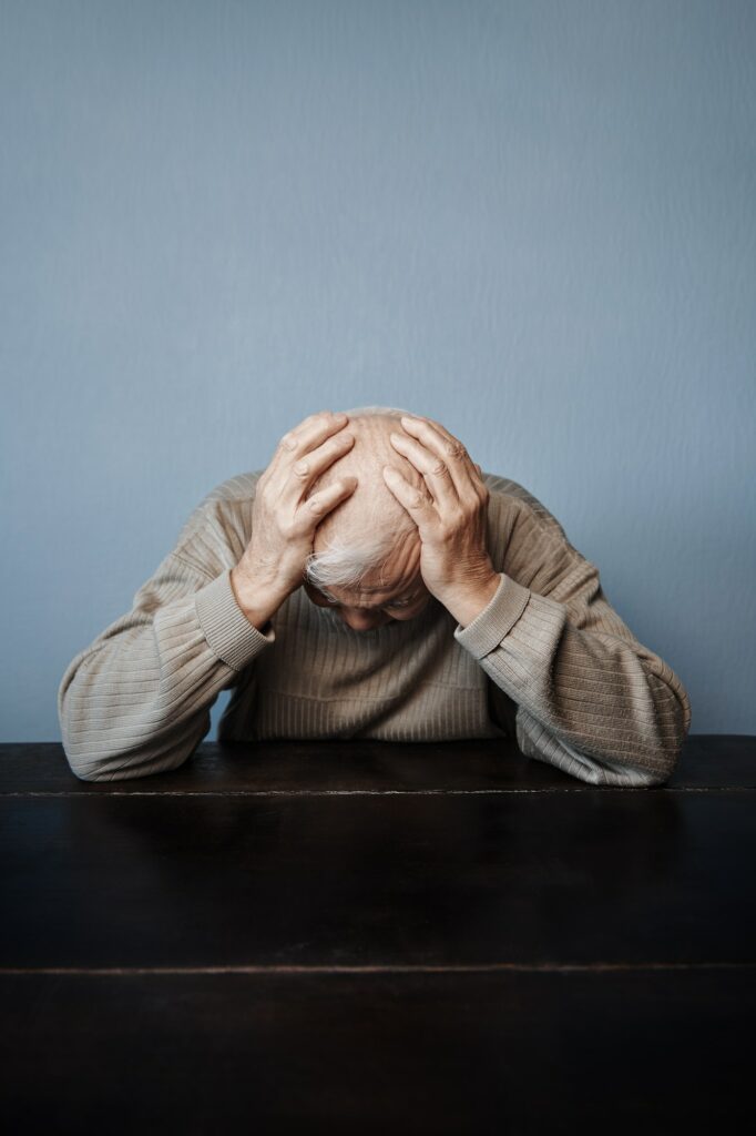 Senior man holding her head in pain while feeling headache